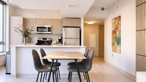 A modern kitchen with a central island, stainless steel appliances, and a dining area with four chairs. - Wow! 5 min to DC/Metro/Mall Stunning 2B King Bed Pool Gym (Arlington)