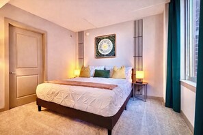 A hotel room with a large bed, two bedside tables, a wall clock, and a decorative wall piece. - Wow! 5 min to DC/Metro/Mall Stunning 2B King Bed Pool Gym (Arlington)