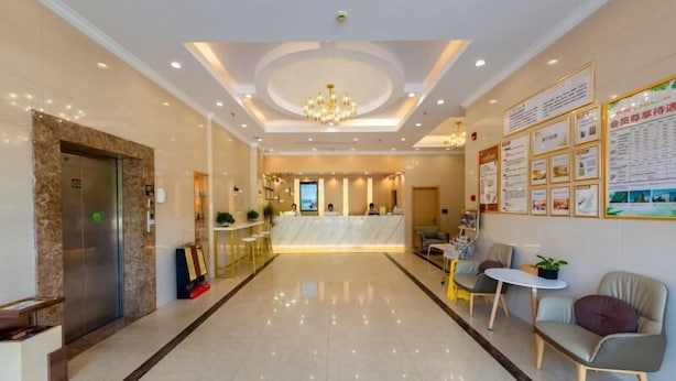 A hotel lobby with a reception desk, seating area, and an elevator. - Greentree Inn Zhonggang City Express Hotel (Jiaxing)