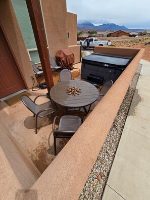 Une terrasse extérieure avec une table ronde et des chaises, un barbecue et une vue sur les montagnes.