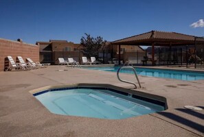 Une piscine avec des chaises longues et un espace équipé d’un jacuzzi.