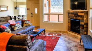 A living room with a sofa, coffee table, and fireplace. - "Solitude De La Sal", Private Hot Tub, Pools, Views, Sleeps 8 (Moab)