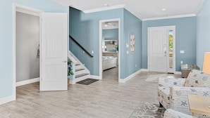 Amplia sala de estar con escalera, un sofá y una puerta que da a otra habitación.