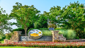A sign with 'GlenRiddle' and a golf flag, surrounded by a stone wall and a flower bed. - 🏖️ Spectacular and Spacious Townhouse in Resort Community (Berlin)