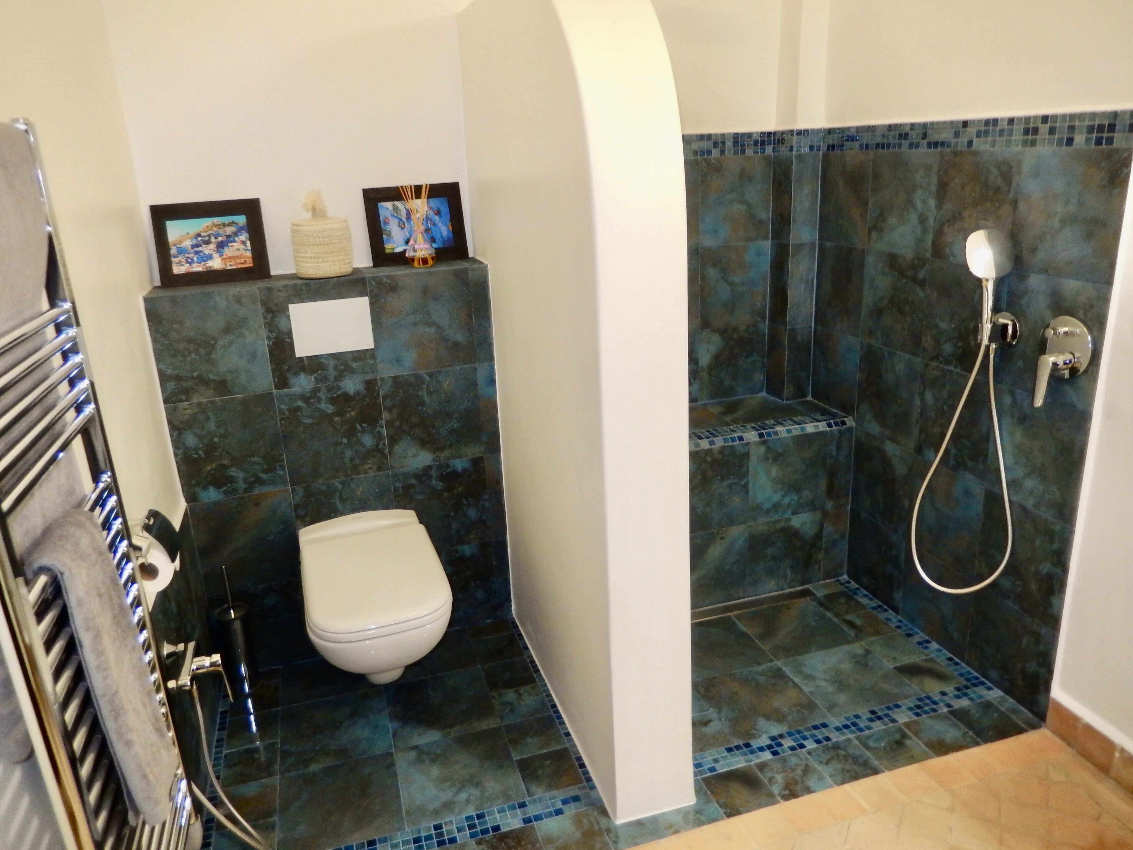 A bathroom with a shower, toilet, and a towel rack.