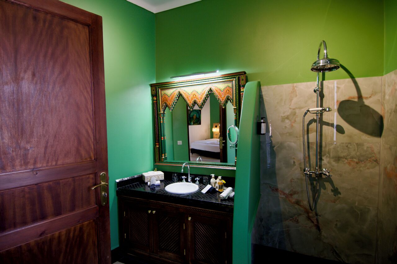A bathroom with a wooden door, a sink with a mirror, and a shower.