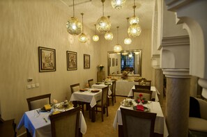 A dining area with tables set for meals, hanging ornate light fixtures, and framed artwork on the walls. - La Claire Fontaine (Marrakech)