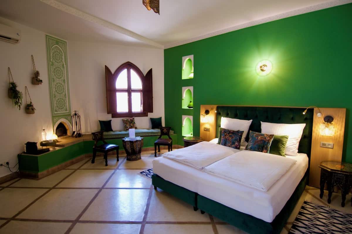 A room with a large bed, a desk, and a window.