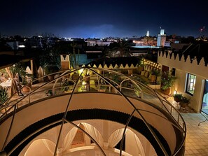 Una terraza al aire libre de varios niveles con una escalera de caracol, plantas en macetas y zonas de estar.