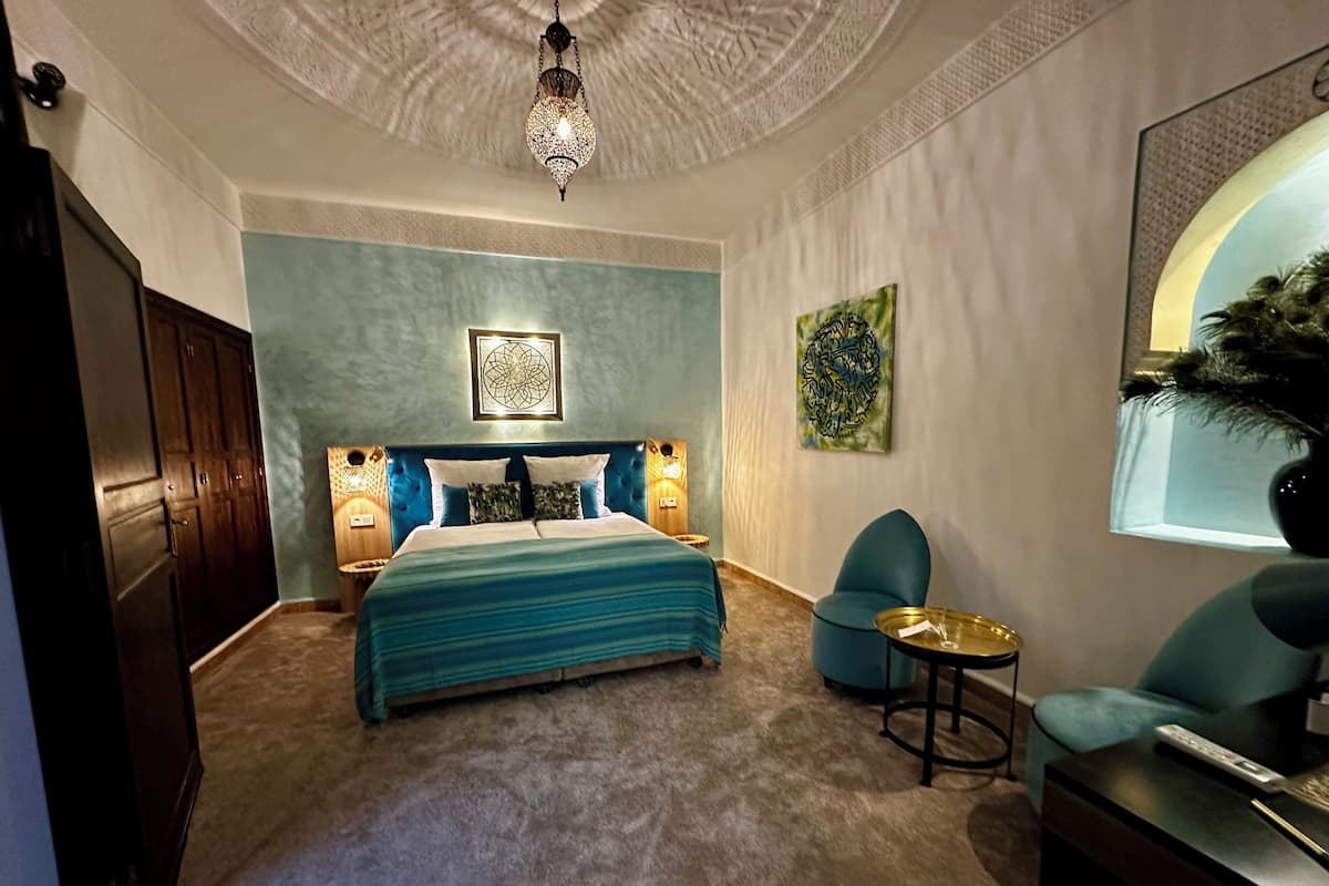 A bedroom with a large bed, a desk, a chair, and a decorative ceiling light.