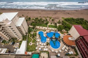 A resort with a large pool area, multiple lounge chairs, and a beach view. - Spectacular Penthouse at 5 Star Resort (Jacó)