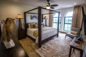 A four-poster bed with a ceiling fan, a stone sculpture, and a view of the outdoors through large windows. - Spectacular Penthouse at 5 Star Resort (Jacó)