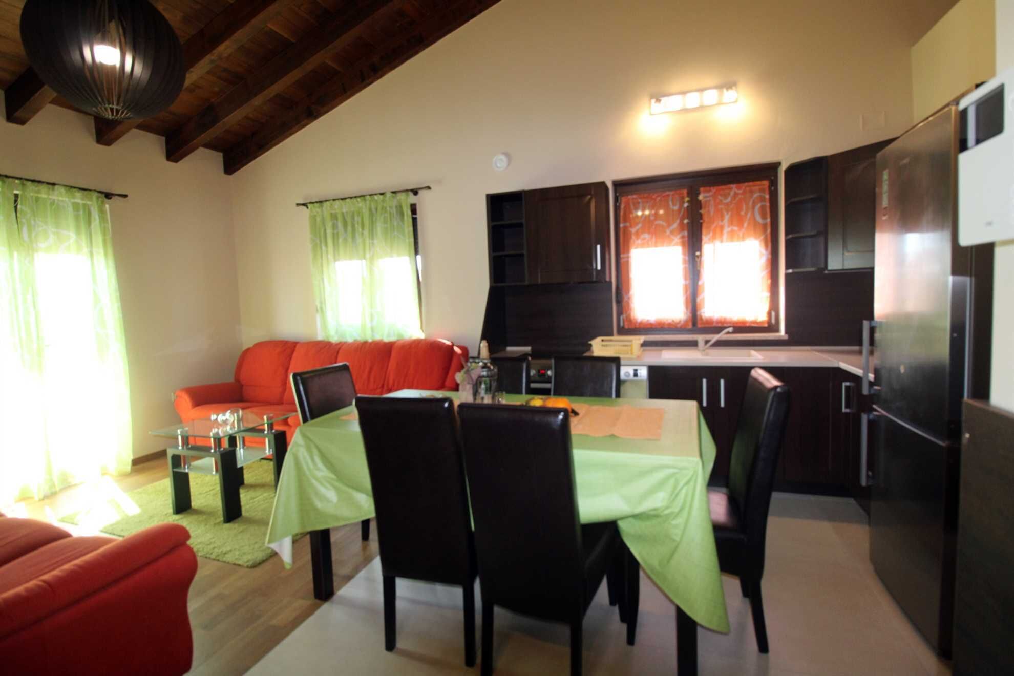 Un ambiente compatto con zona pranzo, cucina e angolo salotto.