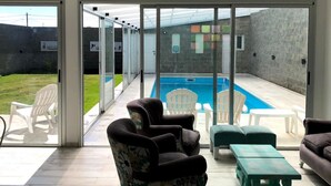 Un espacio interior amplio con piscina, asientos cómodos y un diseño de techo moderno.