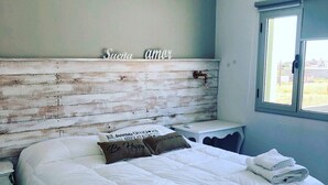 Una cama bien hecha con ropa de cama blanca y dos almohadas, una con un mensaje.