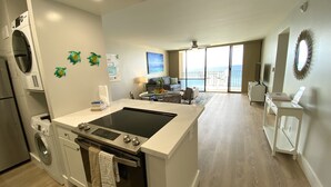 Een moderne keuken met een keukeneiland, inbouwapparatuur en een uitzicht op een balkon.