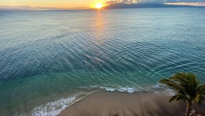 Een strand met helder water en een zonsondergang.