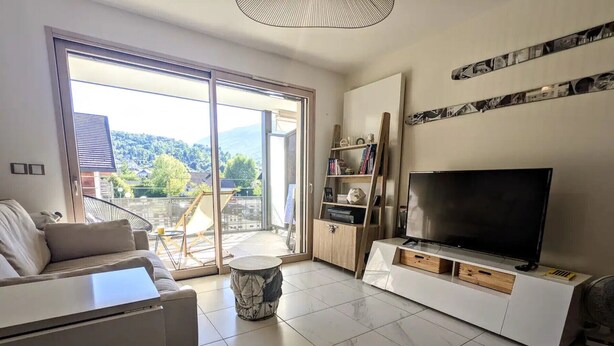 Een moderne woonkamer met een bank, televisie en een balkon met uitzicht.