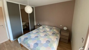 Een slaapkamer met een bed, nachtkastjes, een hanglamp en een kledingkast.