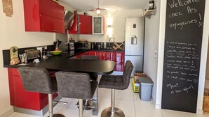 Een moderne keuken met rode kastjes, een zwart aanrecht en een bar met krukken.
