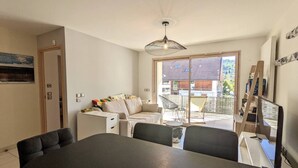 Een moderne woonkamer met een bank, een eettafel en een groot raam.