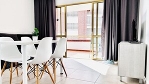 A modern dining area with a white table and chairs, a small potted plant, and a television on a side table. - New Trebol (Benidorm)