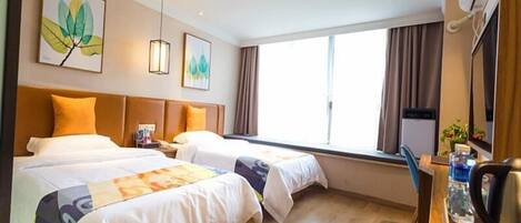 Une chambre d’hôtel avec deux lits, un bureau avec une chaise, une fenêtre et des œuvres d’art accrochées aux murs.