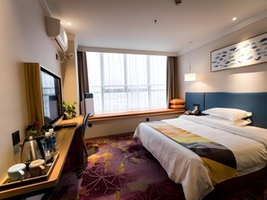 A hotel room with a large bed, a desk with a computer, a TV, and a window with curtains. - Shell Zhengzhou Zhongyuan Fota Hotel (Zhengzhou)