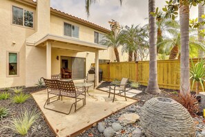 A patio with outdoor furniture, a stone planter, and a yellow fence. - Extended Stay Near Beach! Carlsbad Condo w/ Pool (Carlsbad)