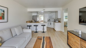 Una sala de estar moderna con un sofá, una mesa de centro y una cocina al fondo.