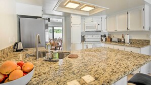 Cocina con encimeras de granito, electrodomésticos de acero inoxidable y armarios blancos.