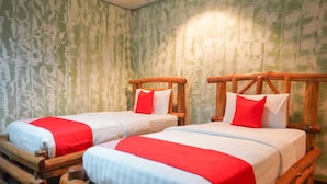 Two wooden beds with red and white bedding, set against a textured green wall.