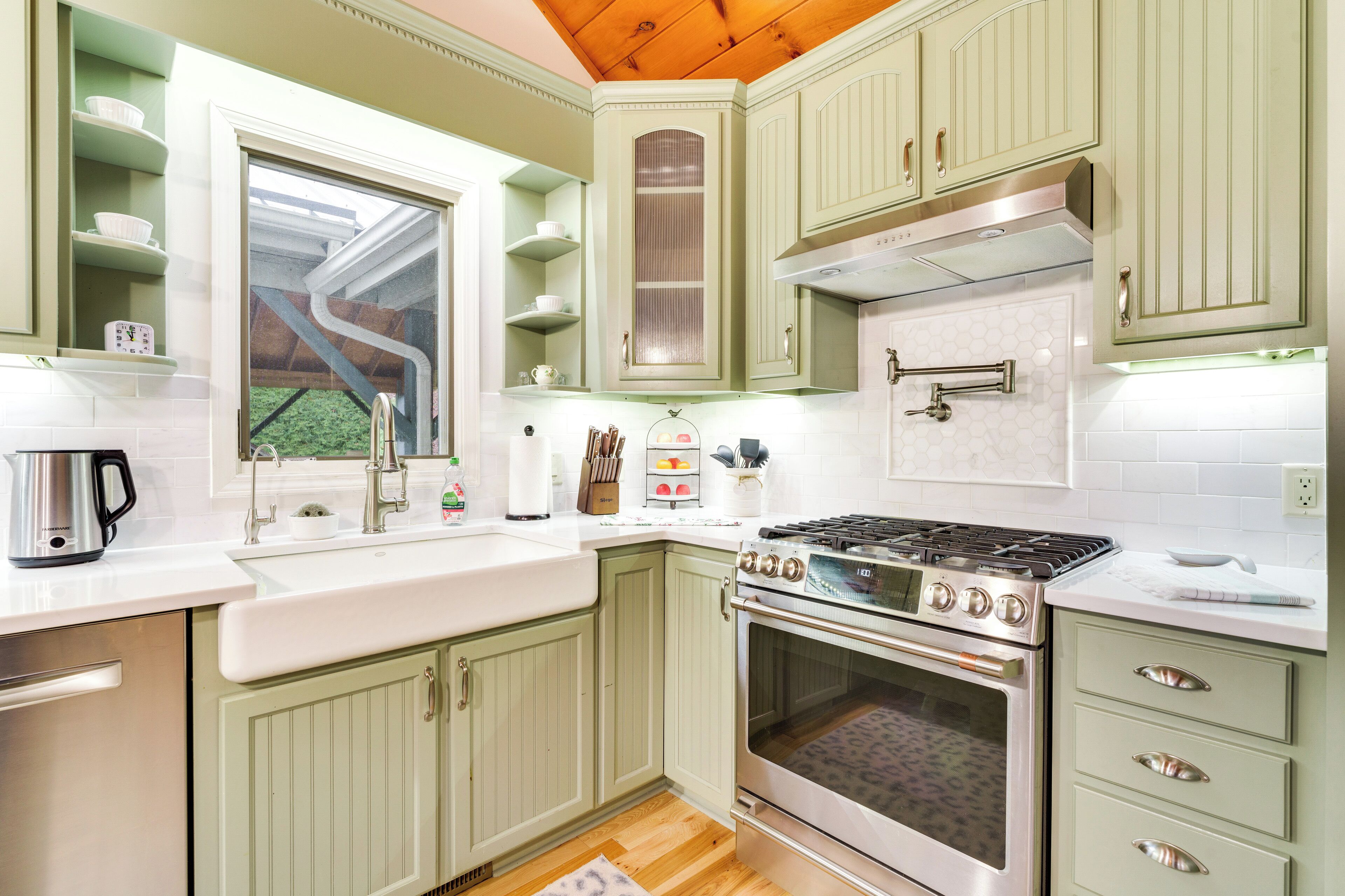 A kitchen with green cabinets, a stove, and a window.