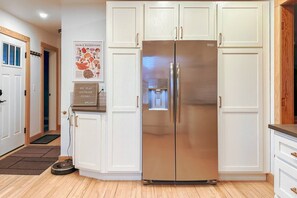 Une cuisine moderne avec des meubles blancs, un réfrigérateur en acier inoxydable et une affiche accrochée au mur.