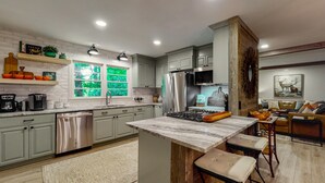 Una cocina moderna con gabinetes grises, electrodomésticos de acero inoxidable y una isla de mármol.