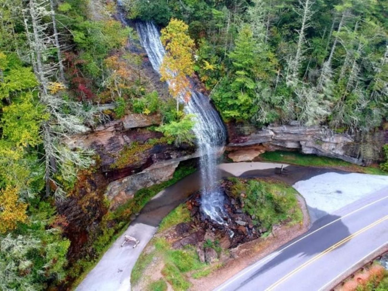 A waterfall cascading over a rocky ledge with a road curving around it.