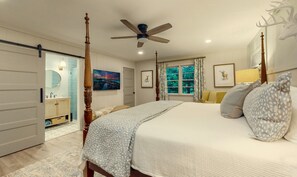 Quarto com cama de dossel, ventilador de teto, banheiro com porta deslizante e janela com cortinas.
