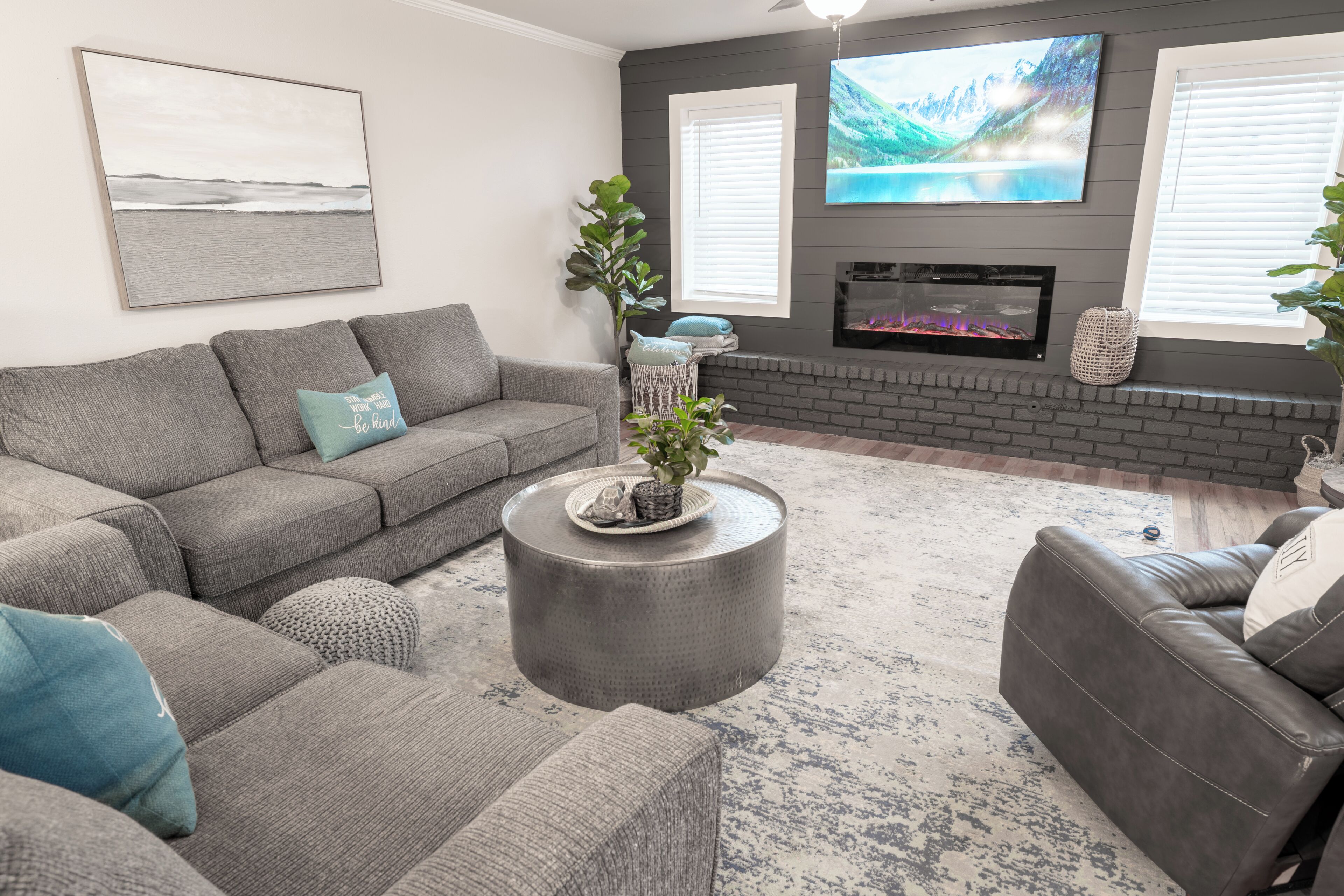 A living room with a grey sofa, a round coffee table, and a fireplace.