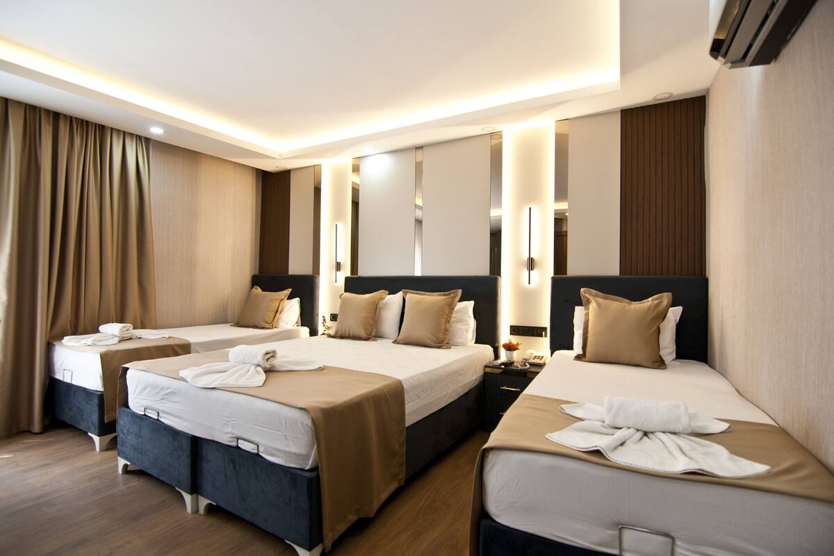A hotel room with two beds, a nightstand, and a mirror.