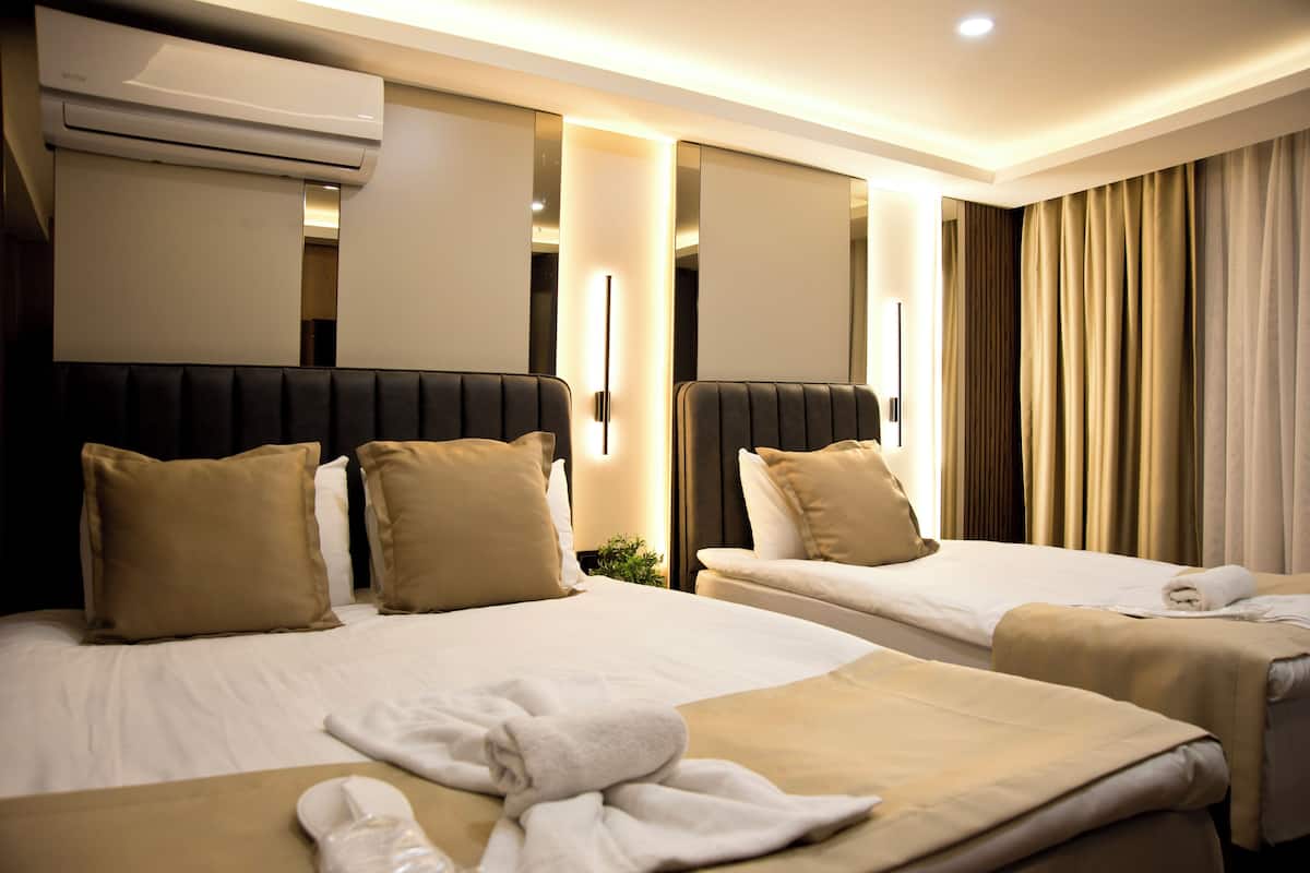 A hotel room with two beds, a large mirror, and an air conditioning unit.