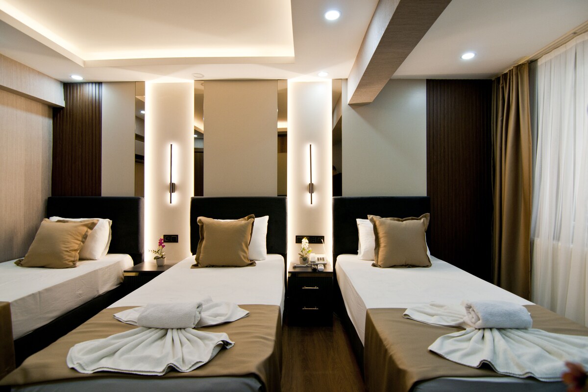 A hotel room with two beds, a nightstand, and a mirror.