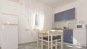 Een keuken met een witte koelkast, een magnetron, een spoelbak en blauwe kastjes.