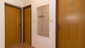 En hall med tre trädörrar, varav en är märkt med en skylt som visar "toalett", och en spegel som är monterad på väggen.