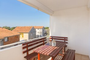 A balcony with wooden benches and a table, overlooking a residential area with houses. - Apartment for six people 1 (Pirovac)