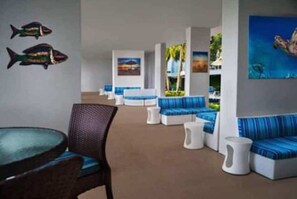 Relax in a comfortable lounge area with cushioned seating and tropical artwork.