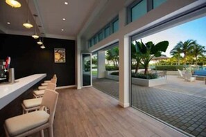 Welcome to our hotel lobby, featuring a long reception desk and comfortable seating area, with a glass door leading to a patio and pool view.