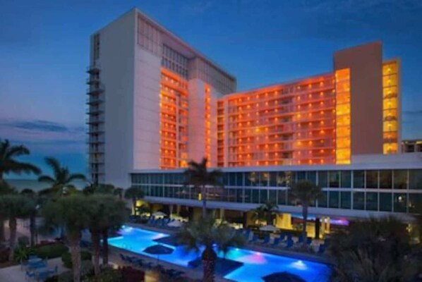 Experience the hotel's modern design with a variety of room layouts and a tranquil pool area surrounded by palm trees.