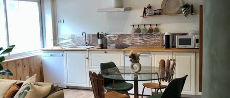 Een moderne keuken met een eetgedeelte, houten vloeren en uitzicht op de omgeving.