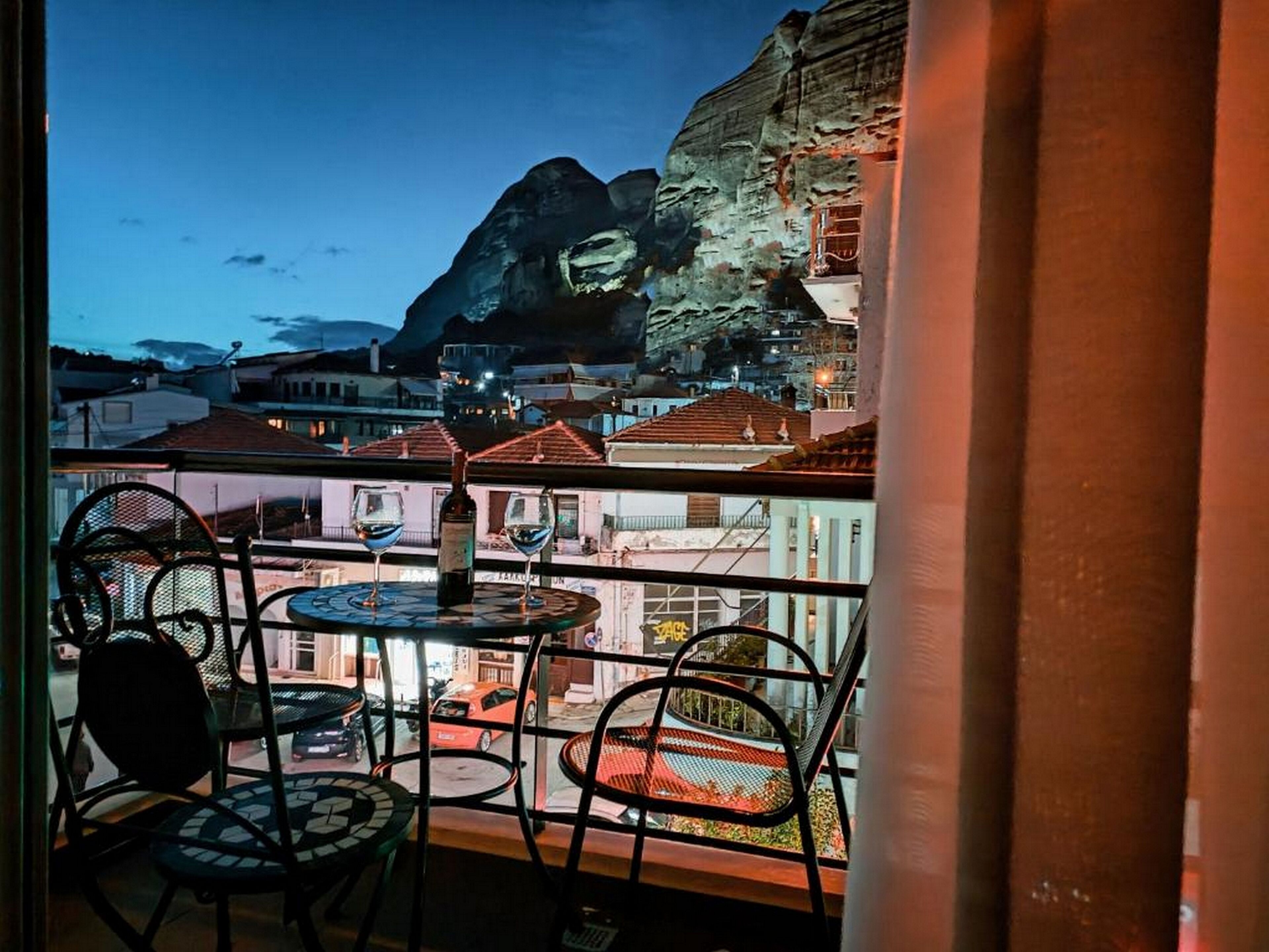 Un balcón con dos mesas y sillas, con vistas a un pueblo y una montaña al fondo.