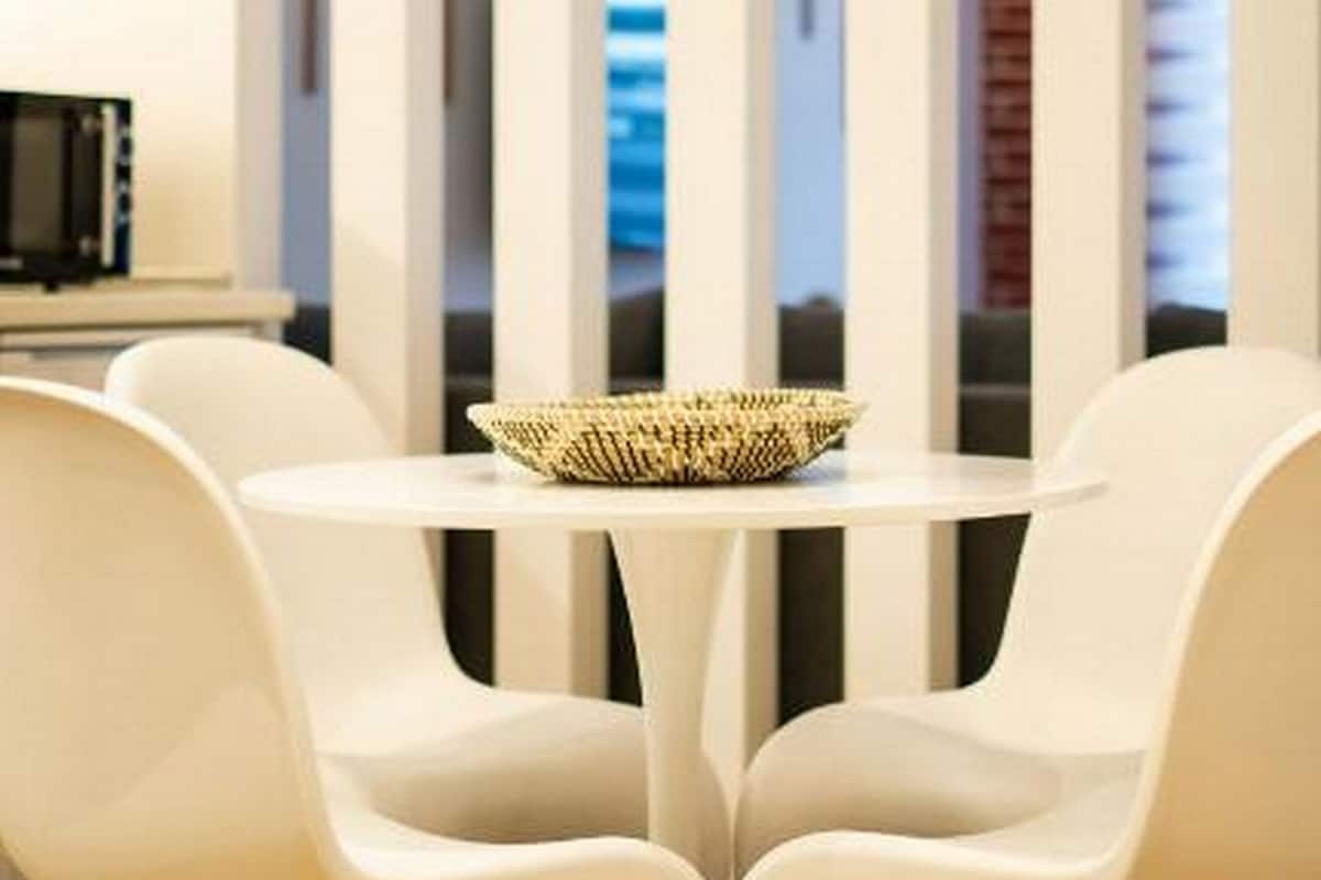 A modern dining area with a round table and two white chairs.